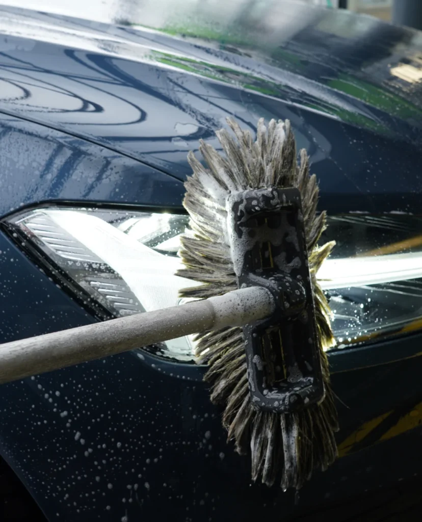 Een borstel die een auto lamp aan het schoonmaken is